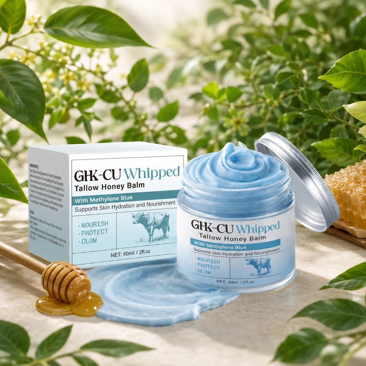 A jar of GIK-CU Whipped Tallow Honey Balm with its box, shown alongside a honey dipper and honeycomb in a natural outdoor setting with green leaves.